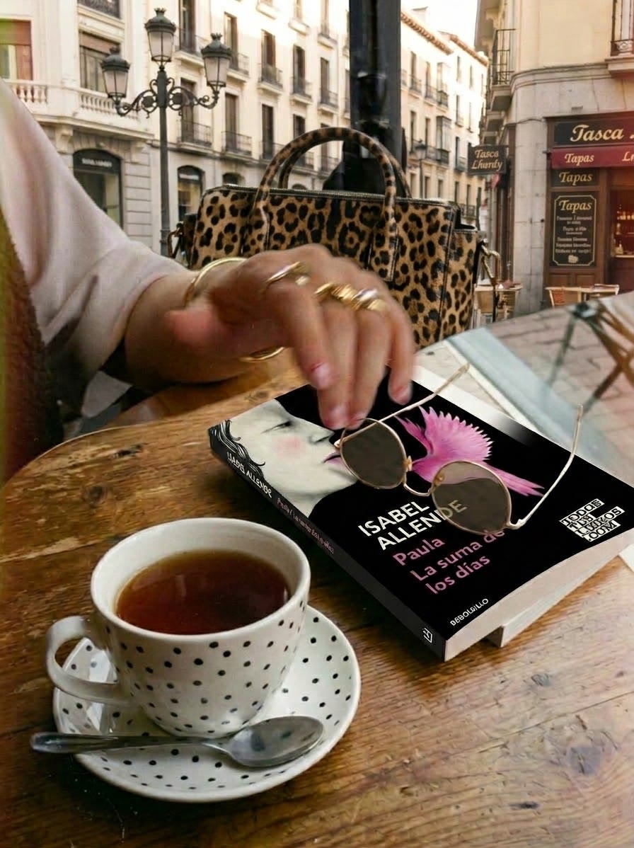 Un té y un libro de Isabel Allende con unas gafas de sol, sobre una mesa de madera